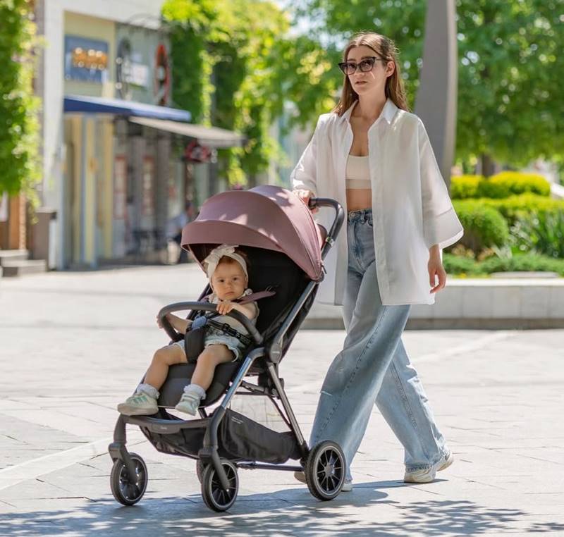 Wózek spacerowy Carrello z pasami bezpieczeństwa, idealny dla dziecka, które zaczyna samodzielnie siedzieć, mama z dzieckiem na spacerze w letni dzień.